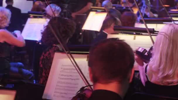 Rock Symphony koncert ukrajinského Tour Kyjev dirigent Nikolai Lysenko houslisté hrají při pohledu na hudbu knihy na stojany osvětlení v koncertním sále — Stock video