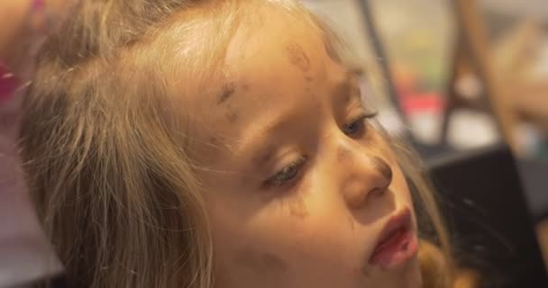 Surullinen pieni blondi tyttö likainen kasvot lapsi istuu luokkahuoneessa taidegalleria ihmiset maali lastentarhassa luokkahuoneessa animaattorit viihdyttää lapsia — kuvapankkivideo