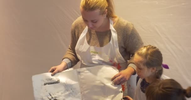 Crianças e mulheres em aventais Professores mostram desenho infantil no final da Master Class Pessoas estão pintando no jardim de infância de arte Educadores de sala de aula Crianças e pais — Vídeo de Stock