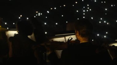 Müzisyenler keman karanlık salonda oynuyor ışıklar müzik kitap standları ışıklı Rock Senfoni konser Ukrayna tur Kiev orkestra şefi Nikolai Lysenko vardır