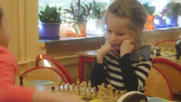 Las niñas preescolares están jugando al ajedrez en el torneo para niños preescolares Organizador "Caballero negro" Los niños están sentados en el juego de mesa de ajedrez en el aula — Vídeos de Stock