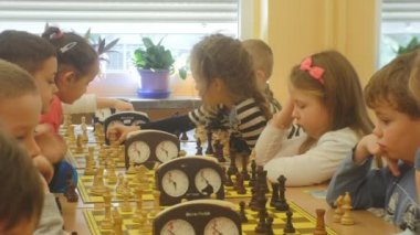 Okul öncesi çocuklar oturuyor Chessboards ve satranç turnuvası için çocuk turnuva Organizatör satranç kulübü 