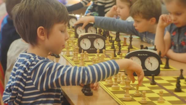 Děti sedí na šachovnicích hrají a hraje šachy turnaj pro předškolního věku děti organizátor šachový klub "black Knight" Opole hra v učebně — Stock video