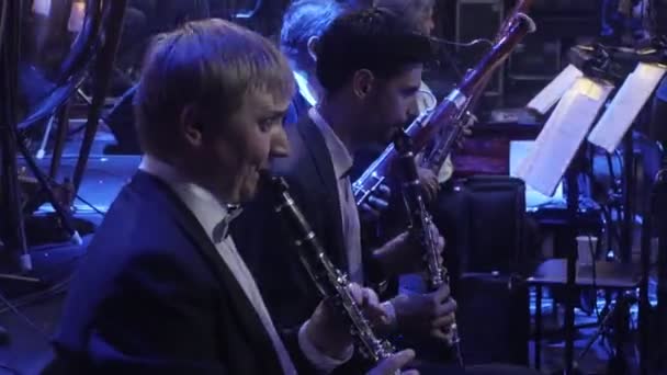 Symfoni konsert Kiev dirigent Nikolai Lysenko rockgrupp män musiker spelar Fagottos fagotter klarinetter musikböcker om står lampor mörk Hall — Stockvideo