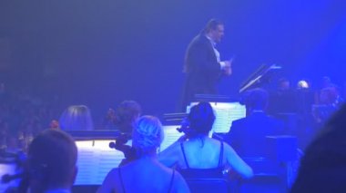 Sallamak Senfoni konser Kiev uzun saçlı adam grup müzisyenler müzik kitap standları mavi yeşil aydınlatma karanlık salon izleyiciler yerlerini üzerinde yürütülmesi