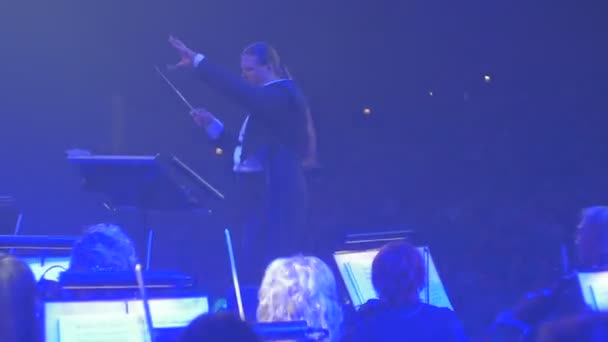 Står rock symfoni konsert Kiev långhåriga mannen genomför gruppen av musiker människor spelar med bågar violinister musikböcker på blå grönt ljus — Stockvideo