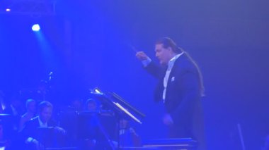 Sallamak Senfoni konser Kiev iletken uzun saçlı adam iletken tutkuyla müzisyenler vardır oynarken müzik kitap standları ritmik ışık efektleri grubudur