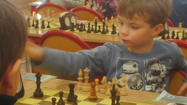 Os meninos do torneio de xadrez estão aprendendo a jogar xadrez crianças sentar-se em frente uns dos outros e fazer movimentos girando sobre o clube de xadrez temporizadores "Cavaleiro preto " — Vídeo de Stock