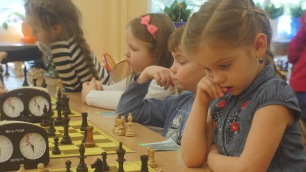 Turnaj pro děti chlapci a dívky hrát šachy děti sedět napříč od navzájem a výrobu přesune zapnutím časovače šachového klubu "Černý rytíř" — Stock video