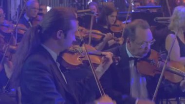 Rock Senfoni konser Kiev grup keman ve ARP adam gözlük uzun saçlı adam mavi lambalar karanlık salon erkek kemancı ön plan üzerinde oynarken müzisyen