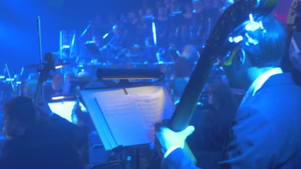 Concerto sinfonico rock Il violoncellista di Kiev gira una pagina di musica Libro in attesa della sua festa Cameraman sta girando Gruppo di musicisti sta giocando illuminazione blu — Video Stock