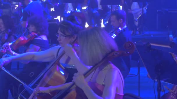 Concierto Sinfónico de Rock Kiev Violinistas Femeninas Panorama de la Orquesta Las mujeres con gafas miran hacia la música Libros sobre soportes Lámparas azules — Vídeos de Stock