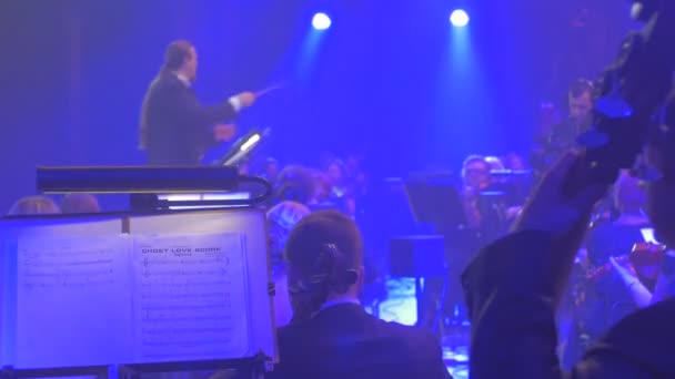 Concert symphonique rock Kiev Man Waves the Baton Violoncellistes Groupe de musiciens à cordes Instruments Chef d'orchestre et orchestre Lumières rouges et bleues — Video