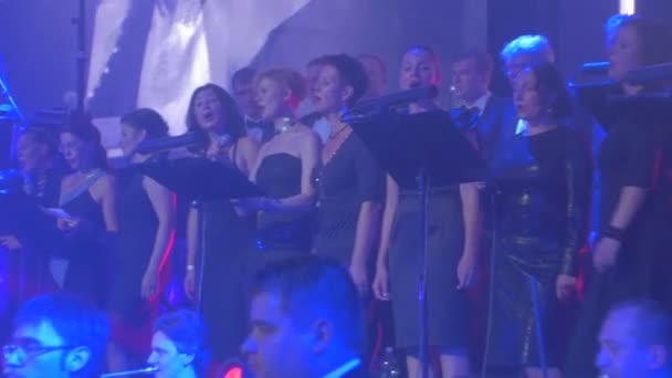 Concerto sinfonico rock Kiev Elegante Coro femminile Acconciature stravaganti Cantanti I musicisti stanno suonando Blue Lights Dark Hall Orchestra Sinfonica Performance — Video Stock