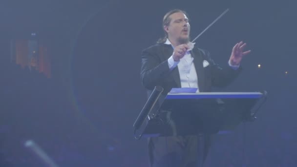 Rock Symphony koncert Kijów dyrygent człowiek wchłania z prowadzenia macha muzyków Baton grają niebieskie światła Orkiestra Symfoniczna powtarzania — Wideo stockowe