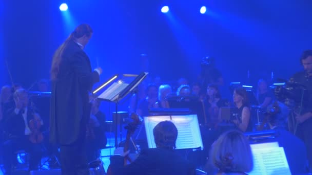 Sallamak Senfoni konser Kiev uzun saçlı adam Baton müzisyenler ile sallayarak Orkestrası iletken Mavi ışıklar büyük Orkestrası tekrarı oynuyor — Stok video
