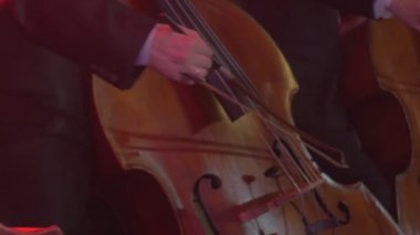 Erkek el smokin güzel ahşap dize enstrüman Rock Senfoni konser Kiev Senfoni Orkestrası çello yayları iyi giyimli müzisyenler ile oynuyorlar