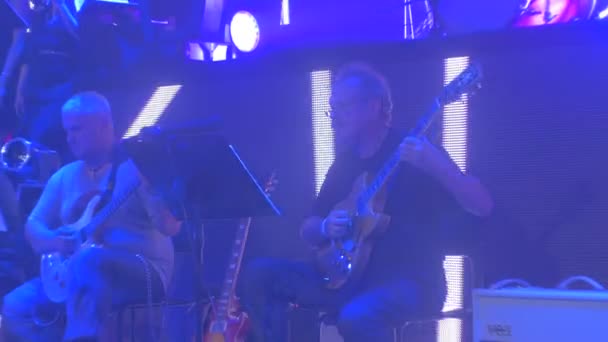Rock Symphoniekonzert Kiev männlichen Gitarristen Chor Lichter auf einem Bildschirm Musiker spielen Frauen singen Blaulicht dunklen Saal großes Symphonieorchester — Stockvideo