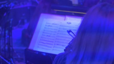 Uzun saçlı kadın oynarken keman müzisyenler seyir içine müzik kitap eğdi aletleri karanlık Hall Mavi ışıklar Well-Dressed oynayanlar konserinde olduğunu
