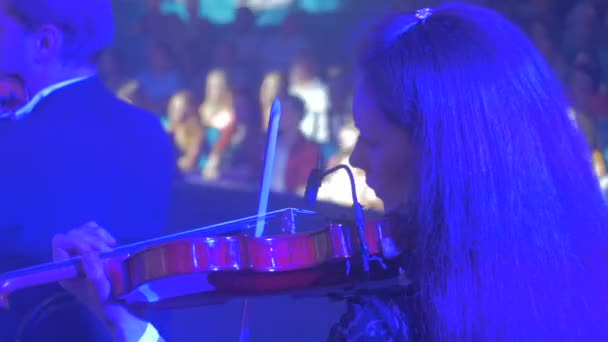Ροκ Συμφωνική απόδοση Κίεβο θηλυκό βιολιστές μακρυμάλλη γυναίκα παίζει βιολί θεατές στο Μέγαρο Μουσικής μουσικά βιβλία στη σκοτεινή αίθουσα στέκεται φωτισμού — Αρχείο Βίντεο