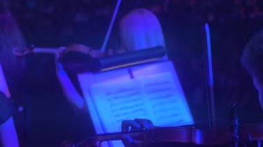 Onların parçası müzisyenler keman mavi ışık müzik kitaplarında Rock Senfoni konser Kiev, standları karanlık Hall izleyiciler üzerinde oynayan erkek kadın kemancılar son