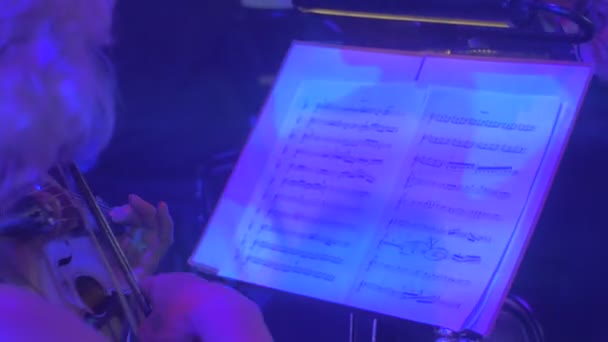 Rubia Violinista está tocando violín Libros de música en soportes Músico está mirando en el libro de música Dark Hall Gente bien vestida en el concierto de Rock Symphony — Vídeo de stock