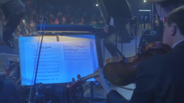 Männer Musikerinnen gut gekleidete Cellisten Geiger in schwarzen Smokings und Abendkleidern spielen Dirigentin winkt den Taktstock Zuschauer auf einem Stuhl — Stockvideo