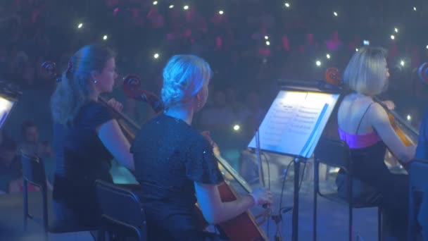 Рок-симфонічний концерт Київські глядачі розмахуючи запальничками натовп добре одягнені музиканти грають поглинається музикою світло включений ритмічні світлові ефекти — стокове відео