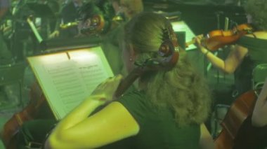 Kadın kemancılar Ans müzisyenler müzik kitap standları uzun saçlı kadın arkası kamera aydınlatma karanlık Hall Rock Senfoni konseri için oynuyorlar