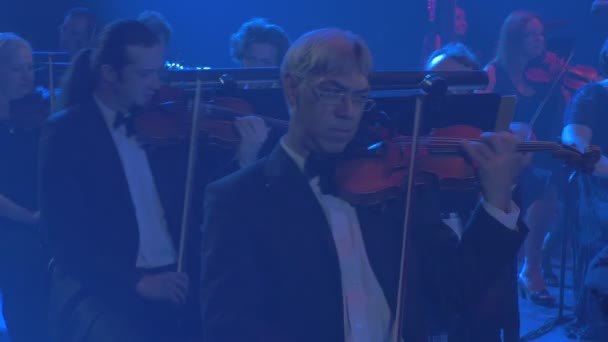 Rock Symphony koncert Kijów Happy Violinists mężczyźni kobiety młody i starszy dobrze ubrany muzycy grają Bowed Instruments patrząc na notatki niebieskie światła — Wideo stockowe
