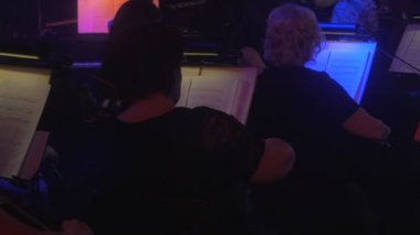 Müzisyenler ile sırtlarına için kamera Kemancılar Müzik oynuyor kitap standları aydınlatma karanlık Hall müzisyenlerin siluetleri orkestra aydınlatılmış