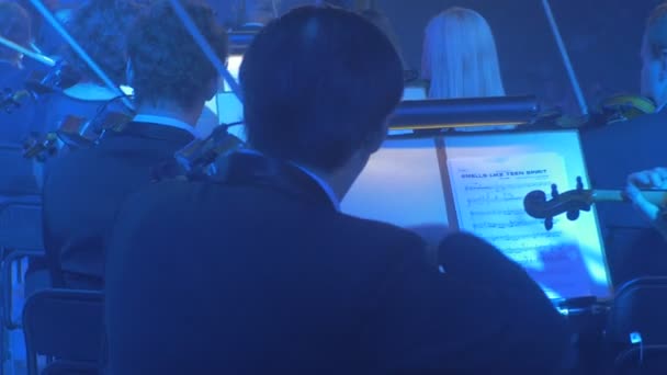 Muzycy grać skrzypiec publiczność jest słuchanie Panorama Orkiestra ciągi ukłonił się instrumenty niebieski lampy ciemne Hall muzyk tyłu Rock Symphony Kijowa — Wideo stockowe