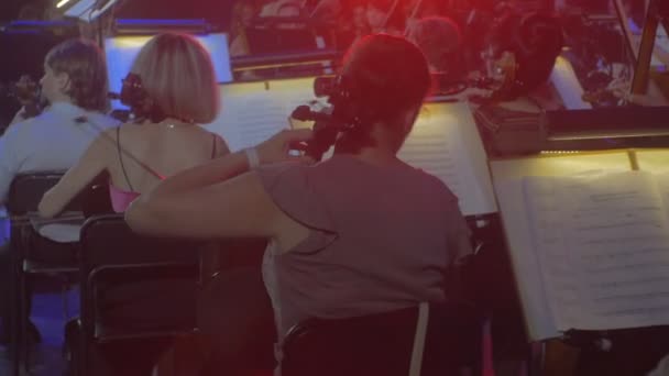 Symphony Concert rockmuzikanten spelen Cellos String familie blauw en rode lampen verlichting Dark zaal vrouwelijke cellisten op voorgrond boeken op een Stands — Stockvideo