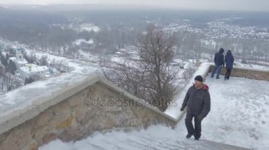 bir orta yaşlı adam Sviatogorsaya Lavra bakan ve sanat konusunda hava atan anıt, gözlem güverte bir merdiven tırmanma Ukrayna'da bulunan kışın