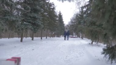 Genç bir çift akşam alacakaranlık karlı kış kırmızı ve beyaz bariyer Gates bir etkileyici köknar ağacı sokak boyunca hareket