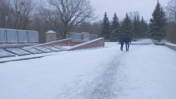 Ein junges Paar, das zu dem 1927 erbauten Denkmal für artyom zieht, das zwanzig Meter hoch ist und im Winter hinter einer Tannenallee steht — Stockvideo