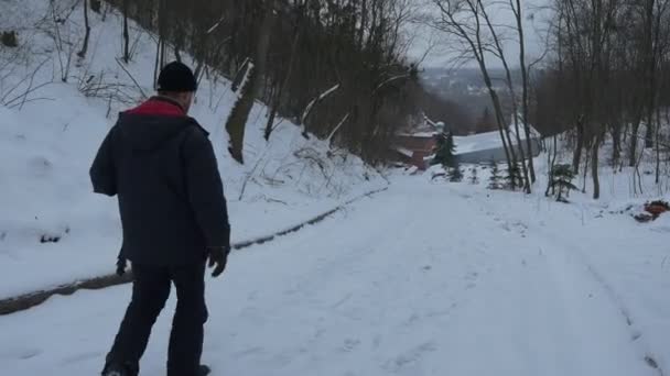 Catedral de Uspensky en Sviatogorkaya Santa Lavra, y un hombre religioso acercándose a ella mientras va a lo largo de un camino peicturesco en medio de las colinas nevadas en invierno — Vídeo de stock