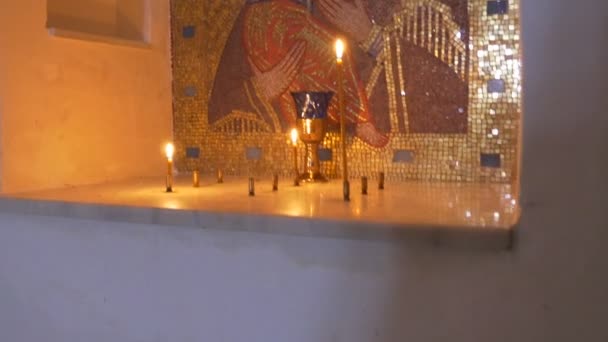 Всемирно известная икона Пресвятой Богородицы с младенцем Иисусом на руках, сделанная из золотистой мозаики со свечами рядом с Мелом Православные пещеры зимой — стоковое видео