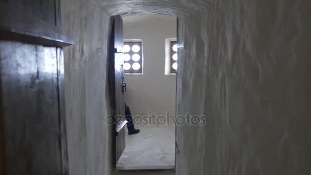 A Man Sitting on a Wooden Bench in Chalk Caves With Semidark Narrow Corridors and Old Wooden Doors Belonging to Sviatogorskaya Orthodox Lavra — Stock Video