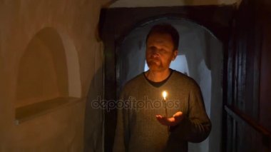 bir dini kahverengi saçlı adam gider boyunca bir Semidark, eski ve dar olan koridor, Saint Mary simgesi, yay aşağı ve haçlar için kendini mağara tapınakta döner