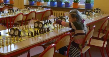 bir tahtaya oturan ve birkaç uzun tablo Chessboards, bir çok kapalı zaman kendisi ile satranç yalnız beş yaşında bir kız saatler