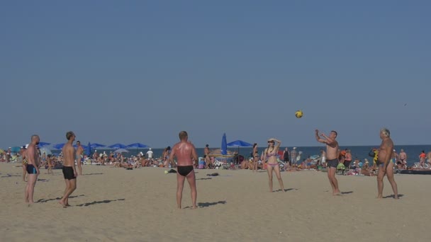 Homens e mulheres jogam vôlei em uma praia — Vídeo de Stock