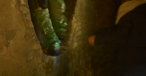Grupa ludzi w butach Chemsuit wspinać się tunel, który jest Semidark, głębokie, Enigmatic, pokryte z betonu i przedstawia odsetki dla bada. — Wideo stockowe