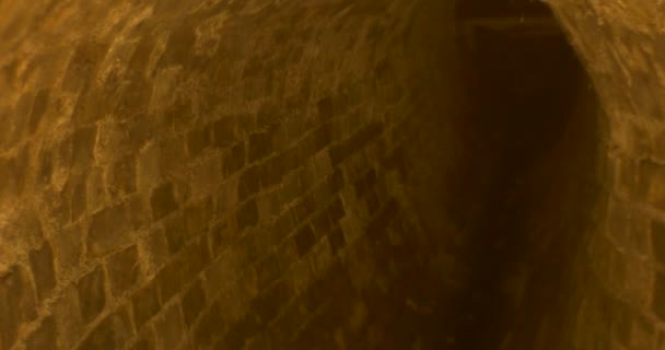 un étroit tunnel semi-arche de briques et de pierres, menant à une extrémité de cadenas, étant éclairé par une lumière scintillante .