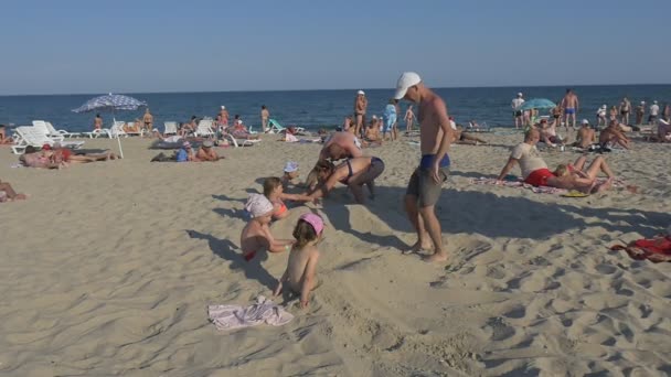 若い男が浜辺で子供と遊ぶこと — ストック動画