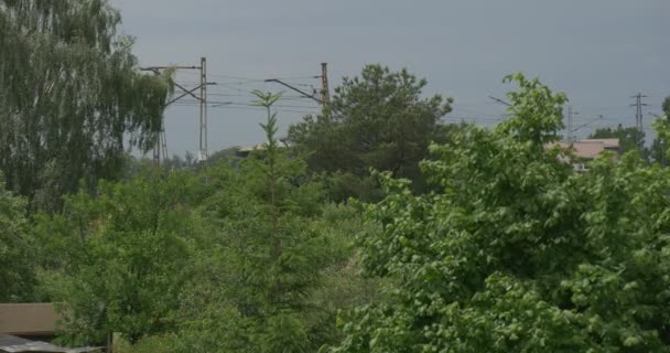 Blå passagerartåg går järnvägen Wire torn längs vägen tak av hus transport elektriskt tåg genom landet landsbygdens landskap — Stockvideo