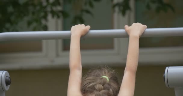 Flickan har klättrat upp på en horisontell Bar — Stockvideo
