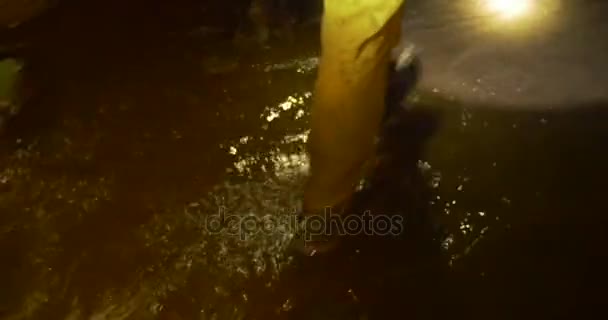 Человек в сапогах идет по тоннелю с ливневой водой, и освещает свой путь мощным фонариком зимой — стоковое видео