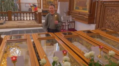 bir adam kendini aşar ve içinde bir Christian Ortodoks kilise olurken bazı Christian Saint Remnats sahip bir cam kutu Kisses