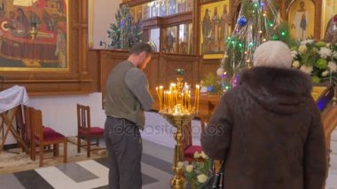 bir adam ve bir kadın dua önce bir ikonostasisin, görünüyor Majestic ile onun altın seyir simgeler, Aziz resimleri, süslü çam ağaçları ve benzeri